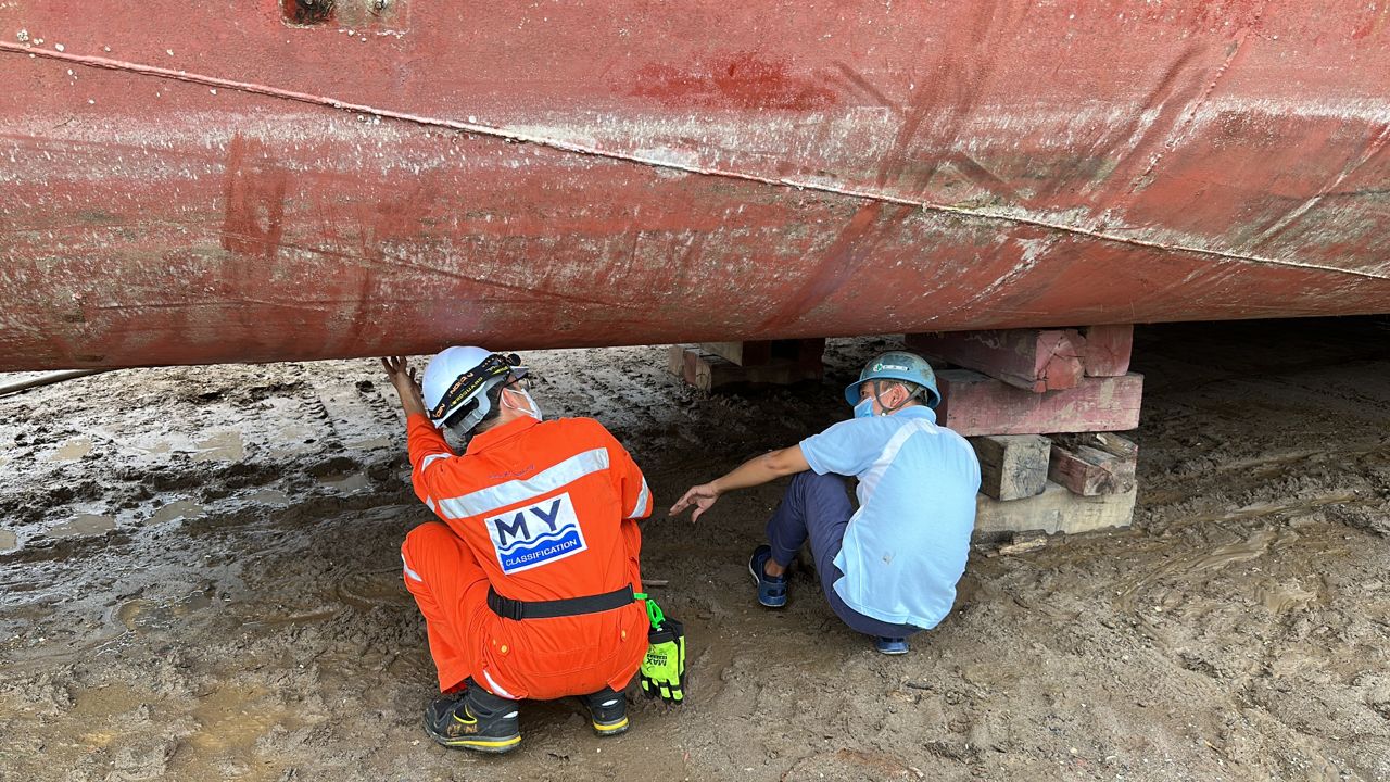Surveyor inspecting a vessel bottom during dry docking