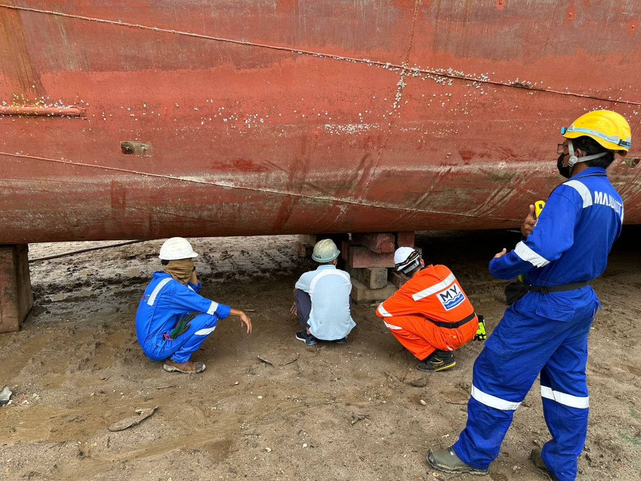 Survey team inspecting a vessel bottom in dry dock